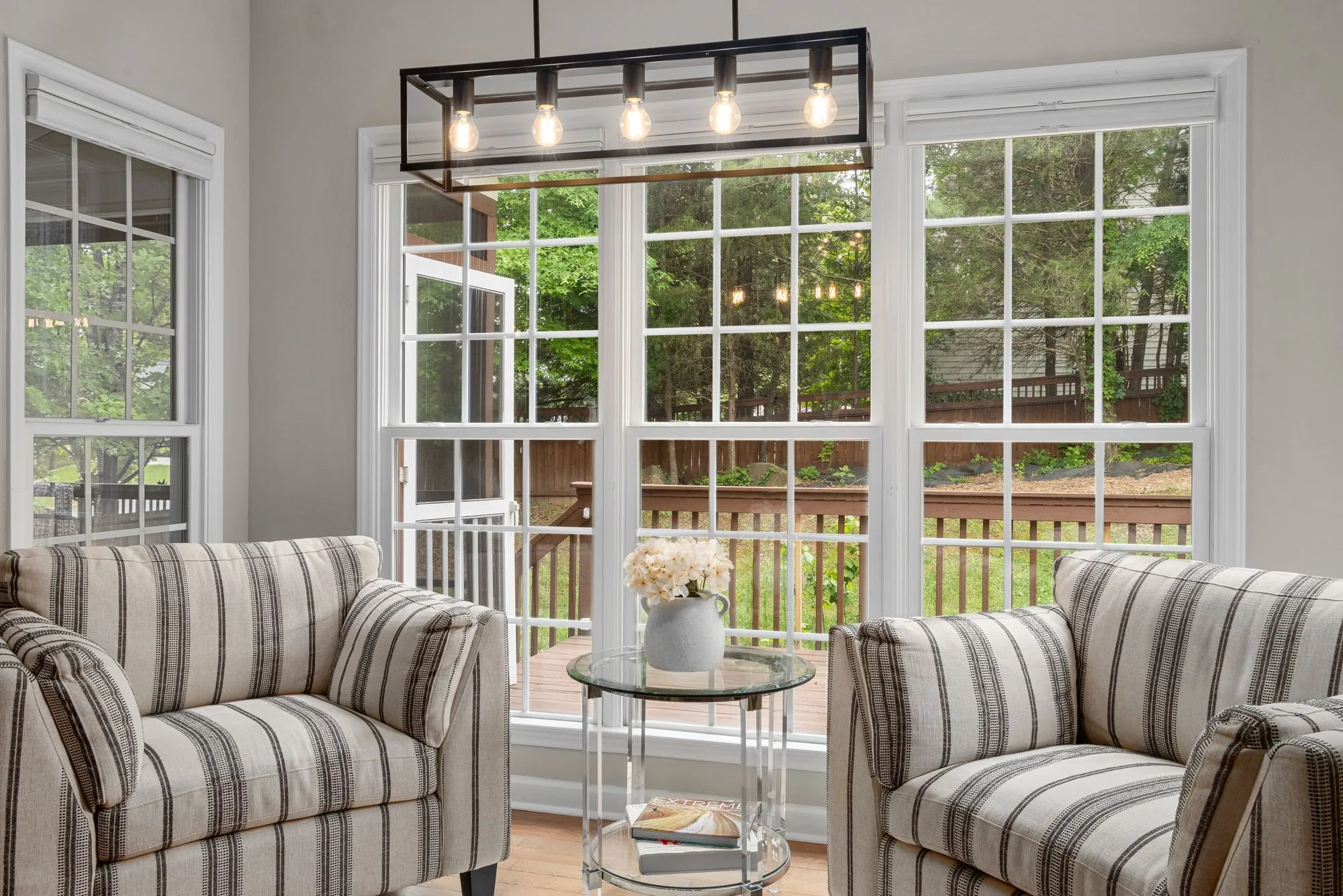 Sunroom with striped armchairs and tall windows onto a deck