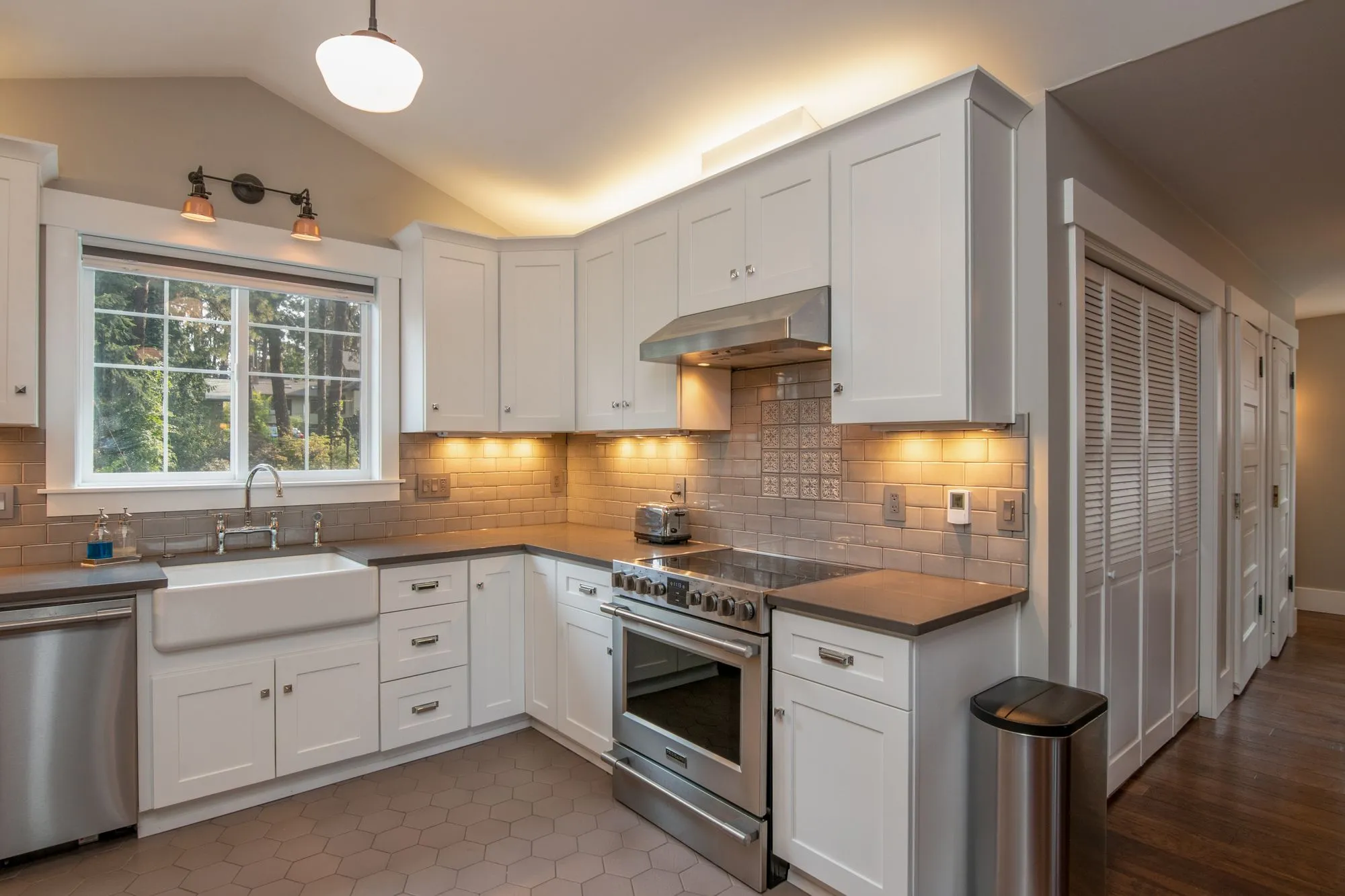 White kitchen with a farmhouse sink under the window and a stainless range